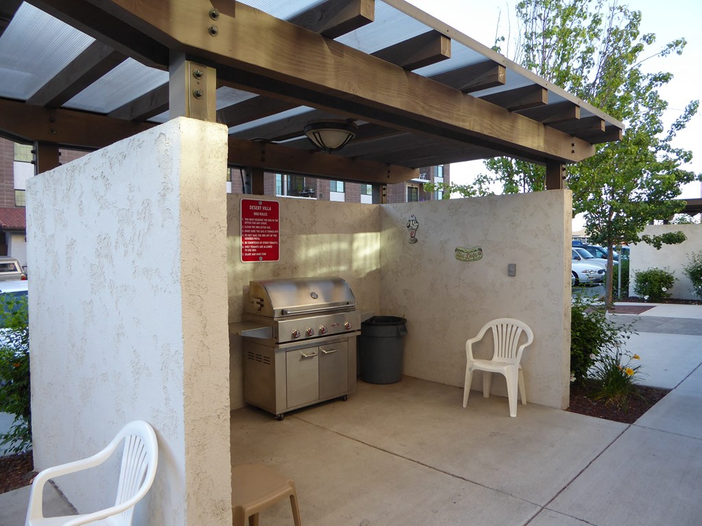 a covered patio with a grill and a table and chairs