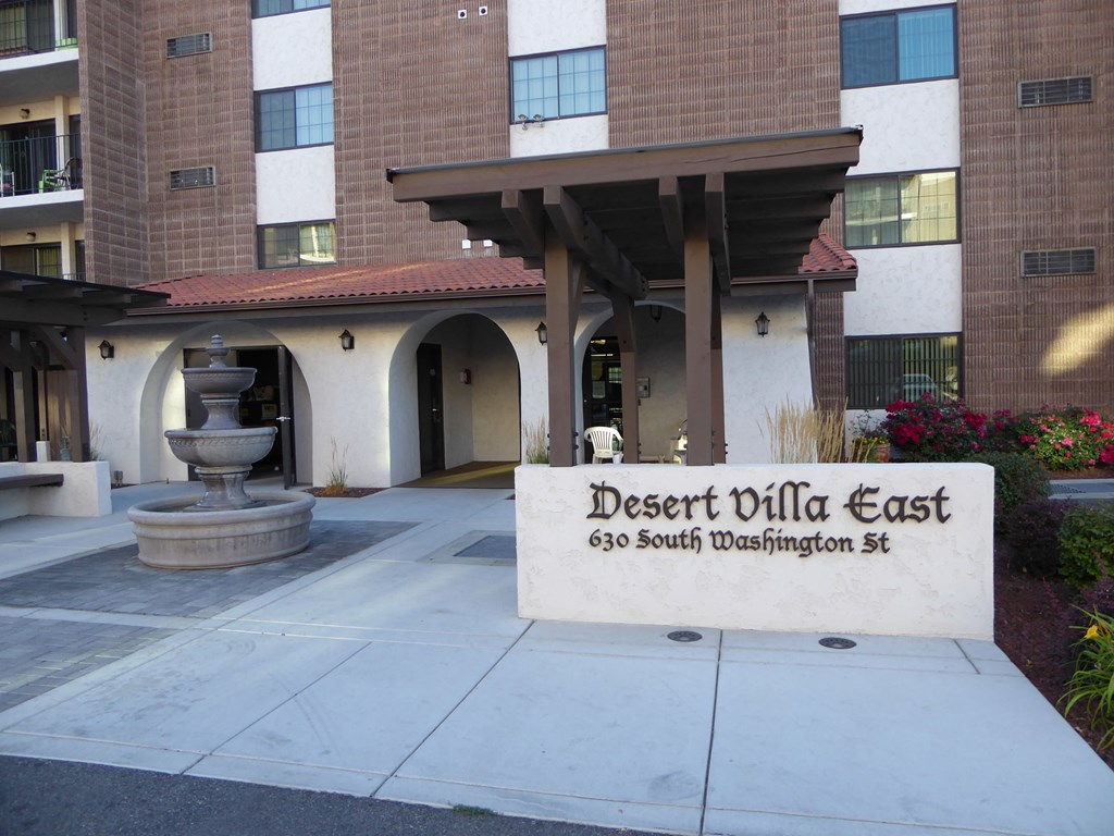 the entrance to the desert villa east building with a fountain in the courtyard