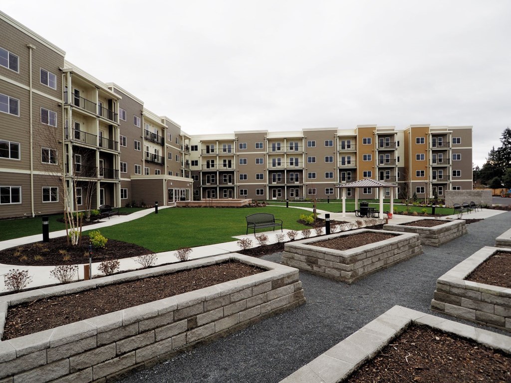 an outdoor area with grass and a lawn in front of an apartment building
