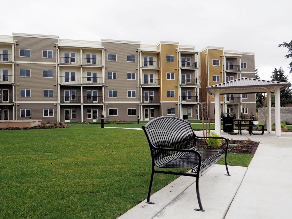 an empty park bench in front of an apartment building