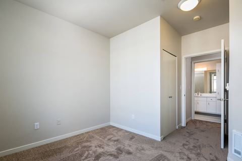 a bedroom with white walls and carpet and a door to a bathroom