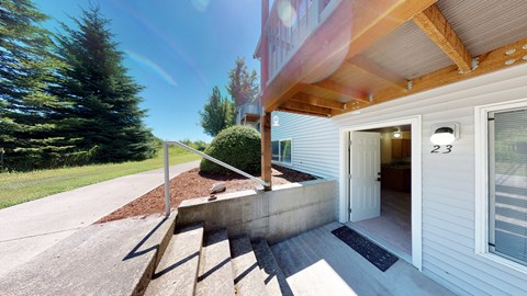 A house numbered 23 with a white exterior and a wooden porch.