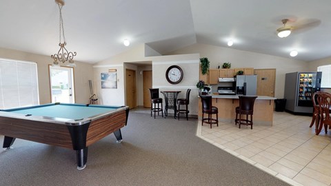 A room with a pool table and a bar area.