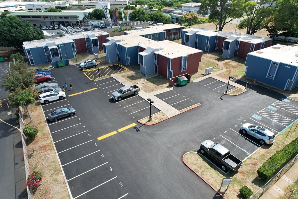 A parking lot with several cars and a building in the background.