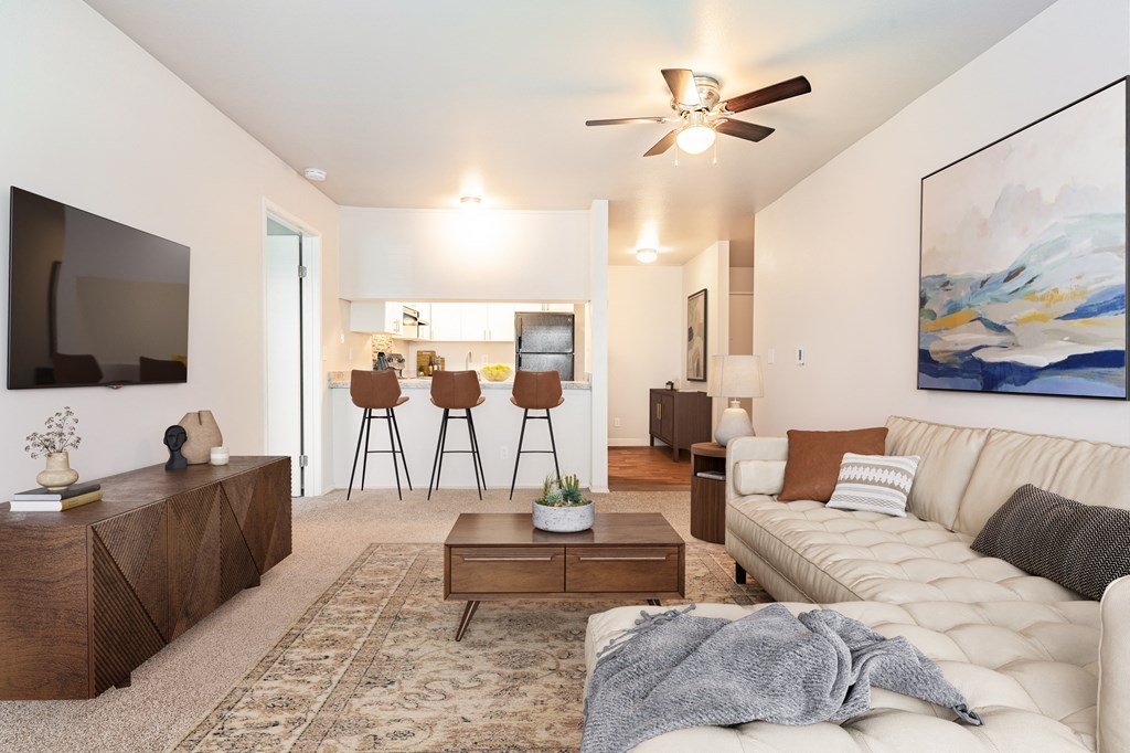 a living room with a couch and coffee table and a kitchen in the background