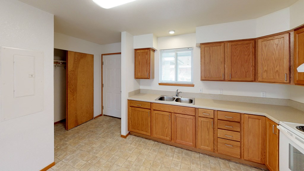 an empty kitchen with wooden cabinets and a sink