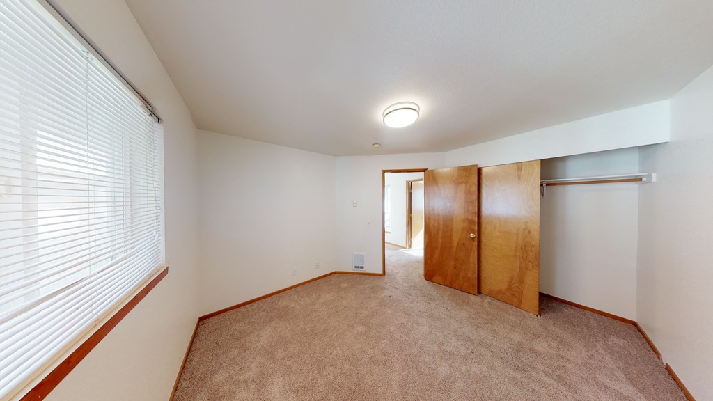 a spacious bedroom with a large window and a closet