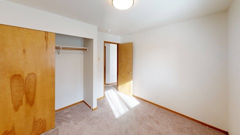 a bedroom with a door to a wardrobe and a carpeted floor