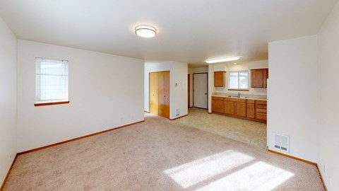 the living room and kitchen of an empty house with white walls and carpet