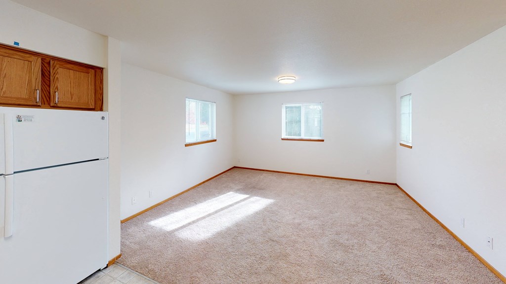 the living room of an empty house with a refrigerator
