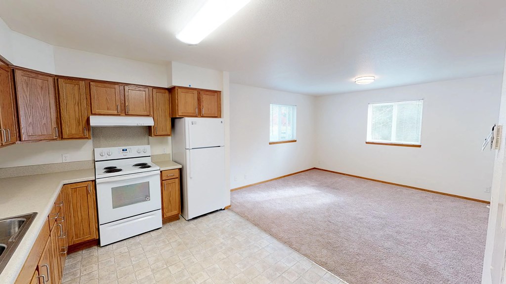 an empty kitchen with white appliances and wooden cabinets