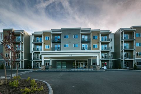 an exterior view of a large apartment building with an empty parking lot