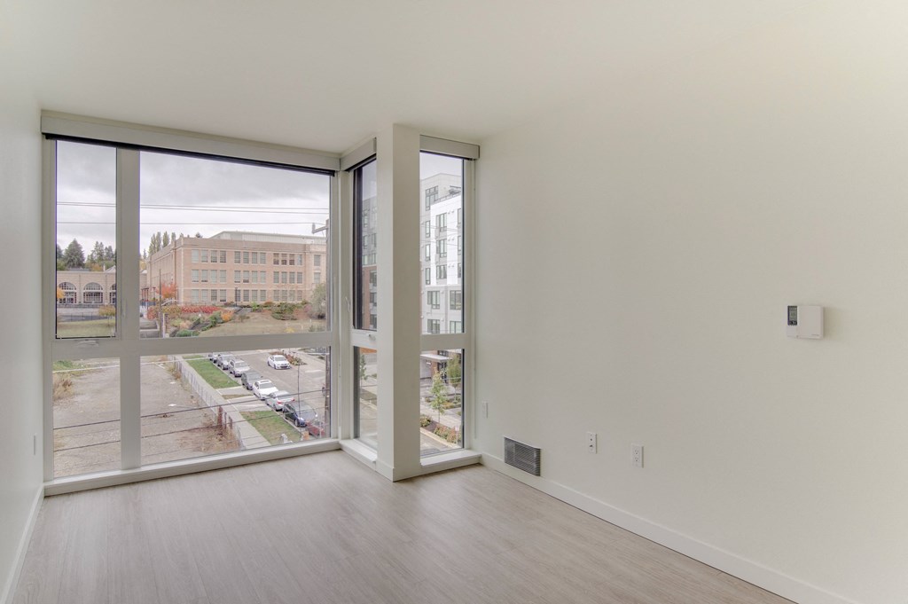 an empty living room with large windows and a city view