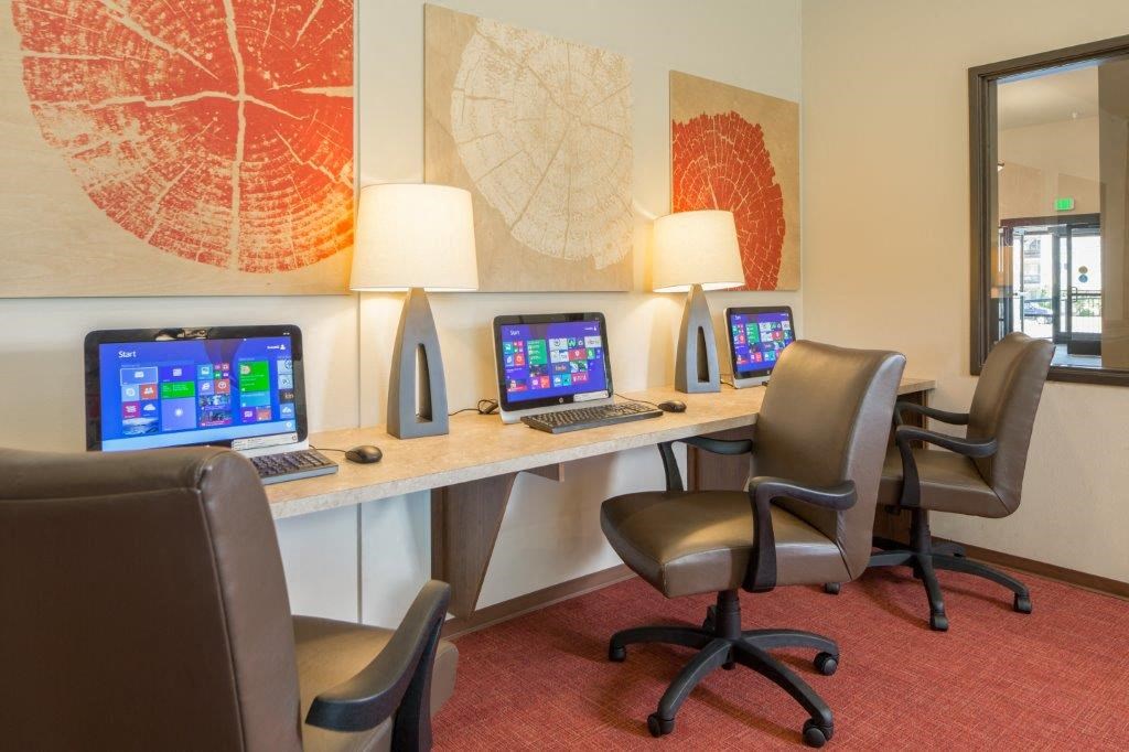a desk with three computers and chairs in a room