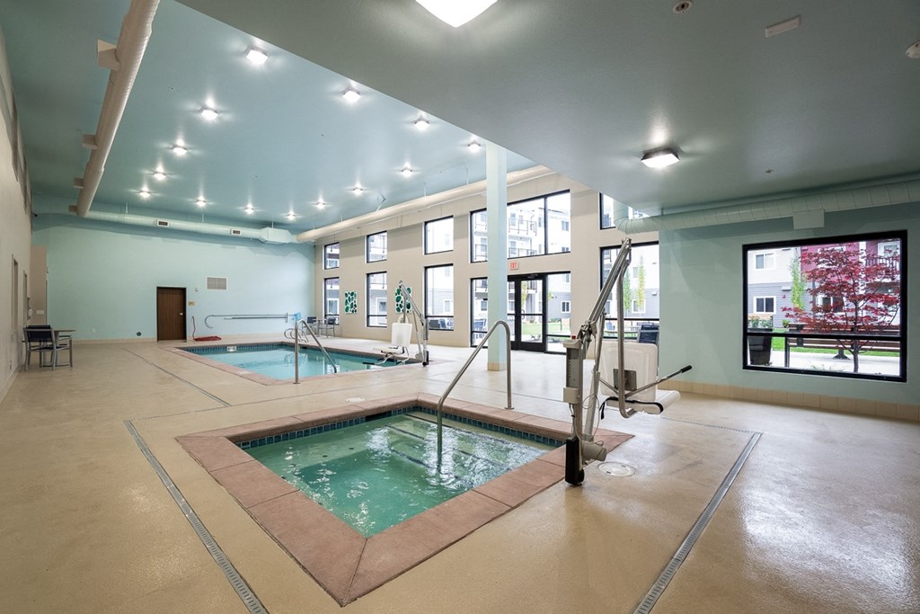 a large indoor swimming pool and jacuzzi in a large room with windows