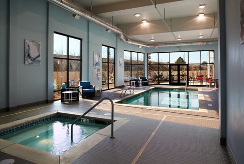 a swimming pool in a large room with glass doors and a windowed pool area