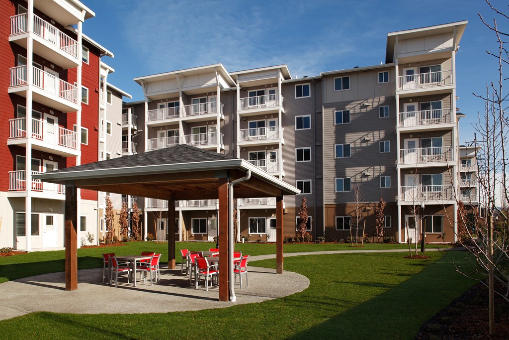 an outdoor area with tables and chairs in front of an apartment building