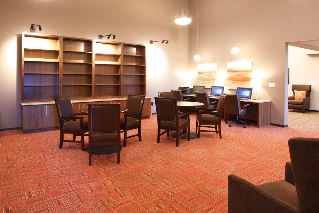 a conference room with a table with chairs and a desk with computers