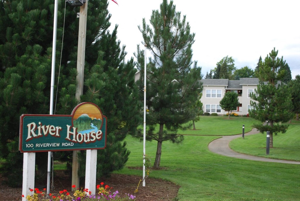 a sign for the river house with a building in the background