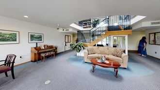 a living room with a staircase in the background and a couch in the foreground