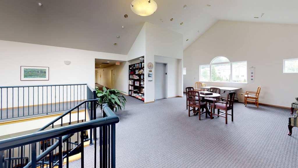 a common room with a table and chairs and a staircase