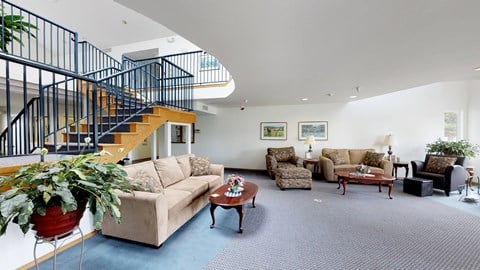 a living room with couches and chairs and a staircase