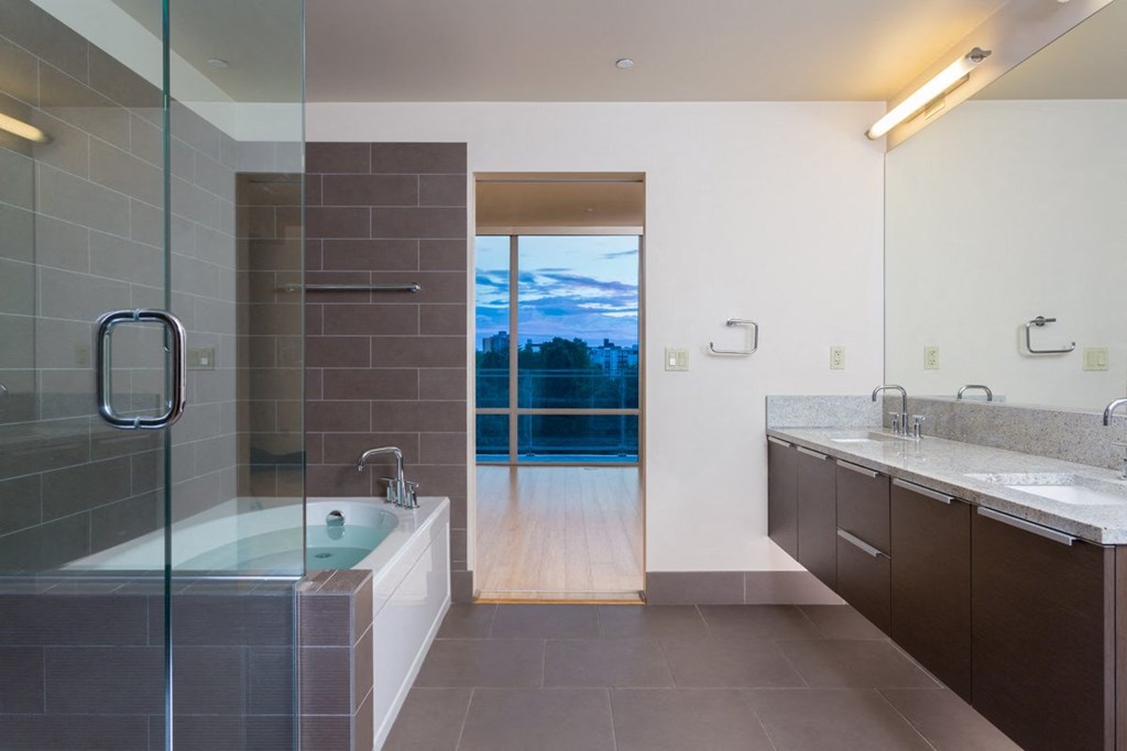 a bathroom with a tub and two sinks and a window