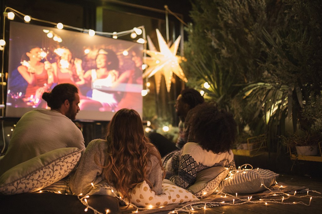 a group of people sitting on the ground watching a movie at a christmas party