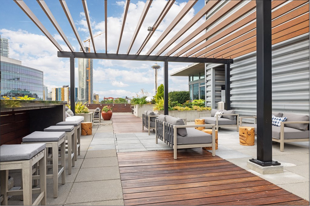 a roof top patio with chairs and a bar and a view of the city