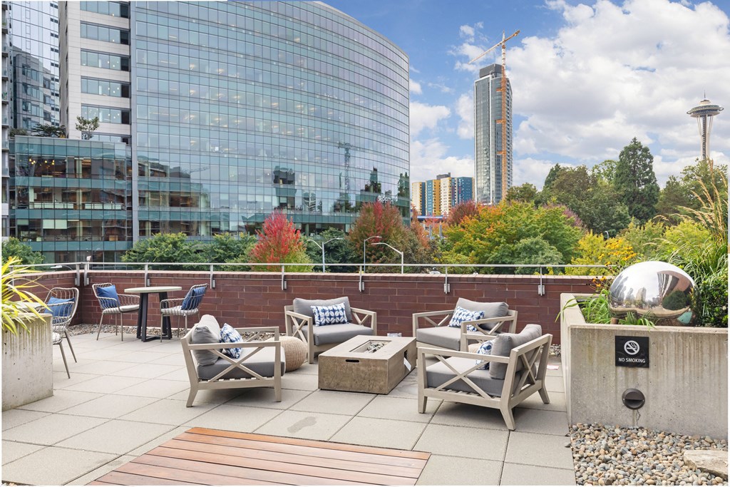 a roof terrace with furniture and a city in the background