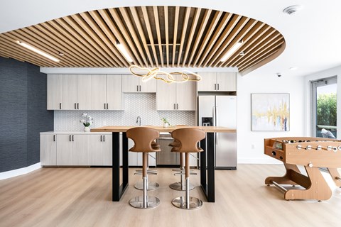 A modern kitchen with a wooden ceiling and a dining table with chairs.
