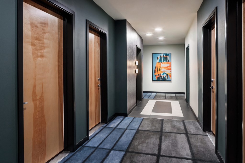 a row of doors in a hallway with a painting on the wall