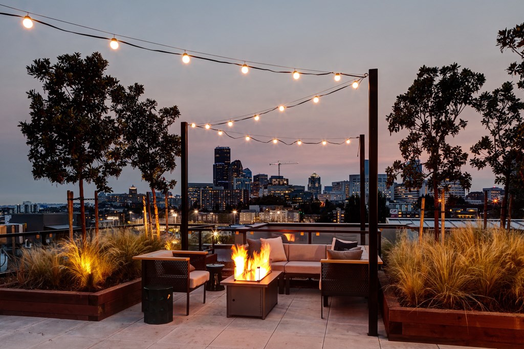 a rooftop terrace with a fire pit and a city skyline in the background