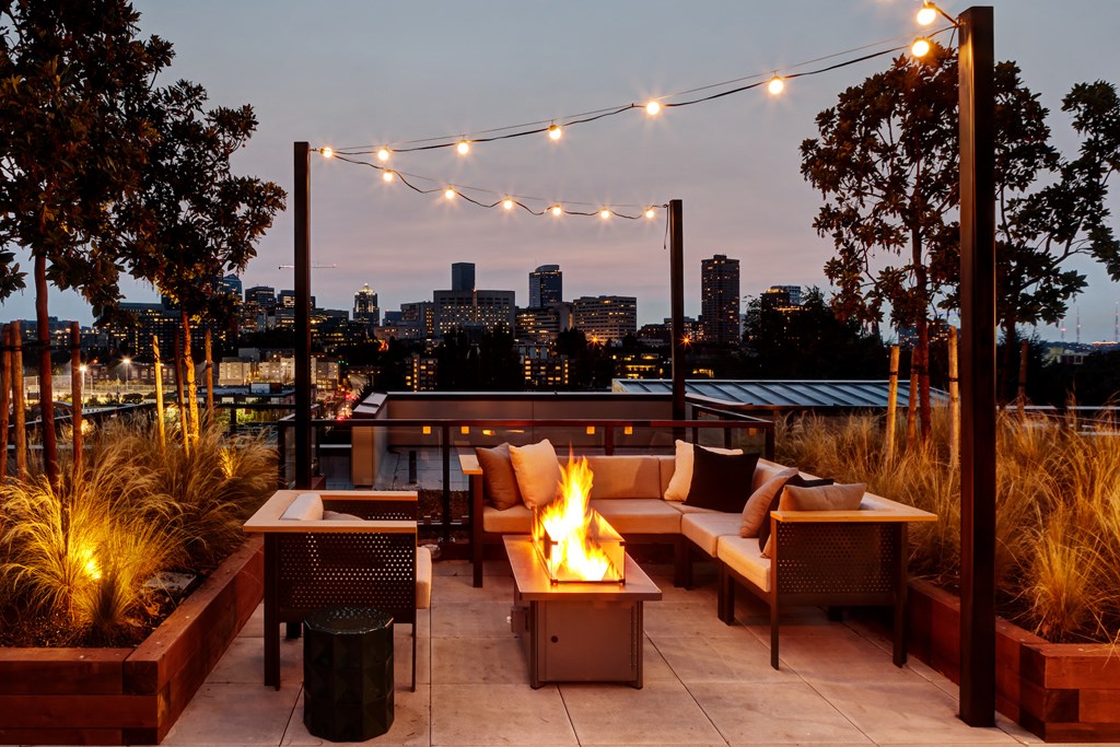 a patio with a fire pit overlooking a city at night