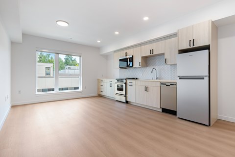 A modern kitchen with wooden floors and stainless steel appliances.