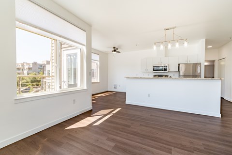 A spacious kitchen and living room with wood flooring and white walls.