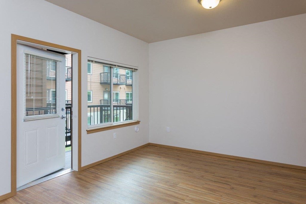 a living room with wood floors and a door to a balcony