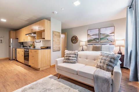 A modern living room with a white couch and a kitchen area in the background.
