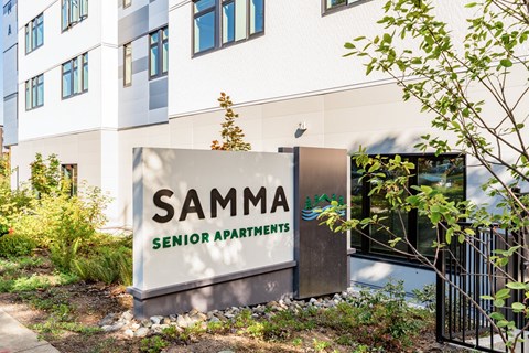 A sign for Samma Senior Apartments is in front of a building.