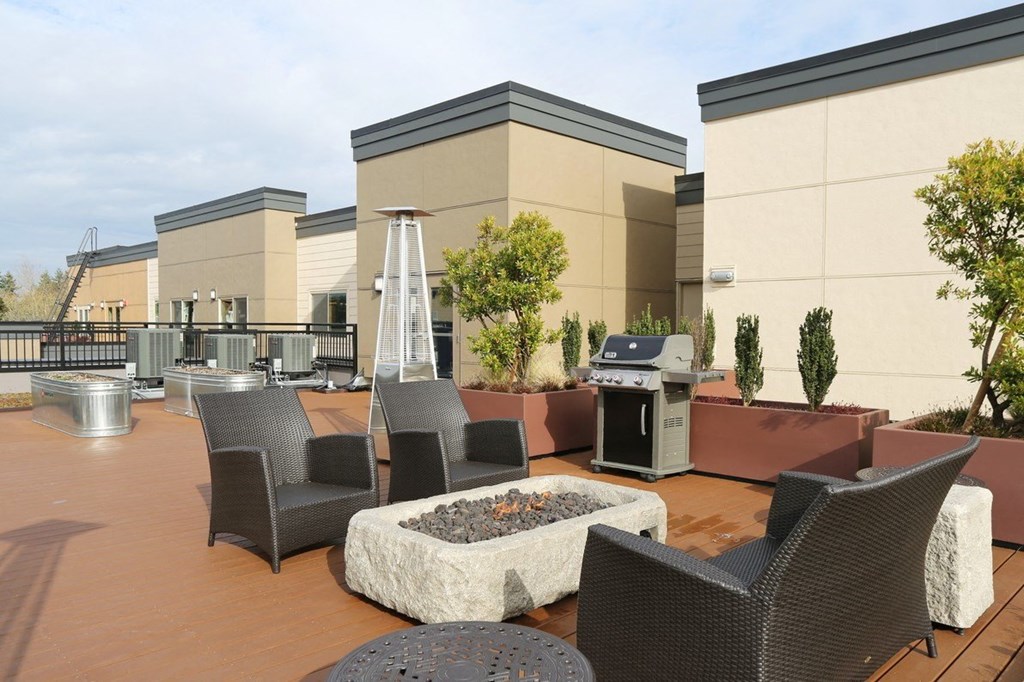 an outdoor patio with chairs and a grill and a fire pit
