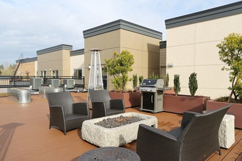 an outdoor patio with chairs and a grill and a fire pit
