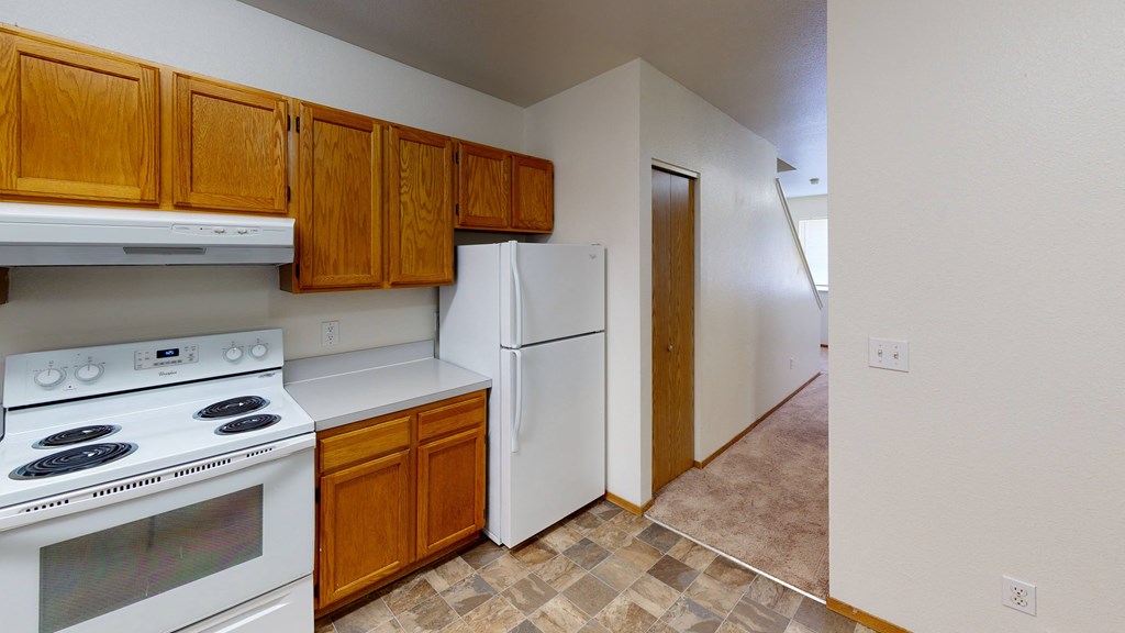 a kitchen with white appliances and wooden cabinets and a white refrigerator
