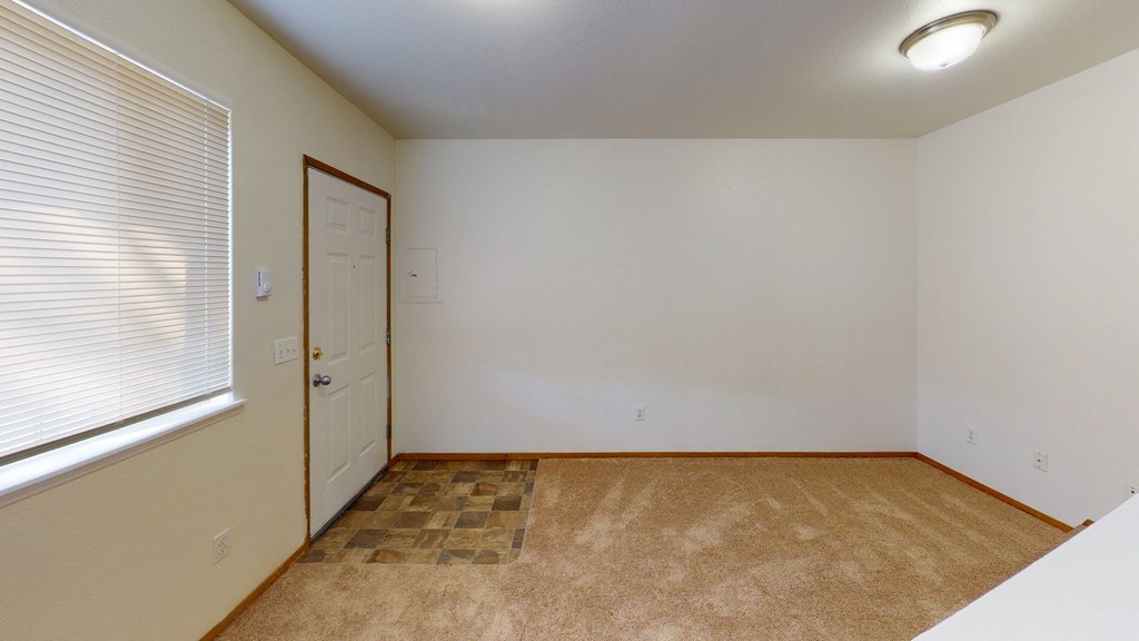 an empty living room with a large window and a door
