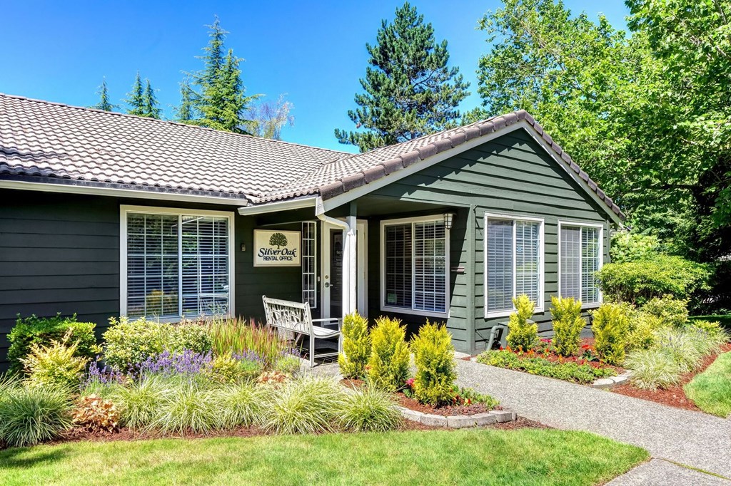 the front of a green house with a yard and a chair