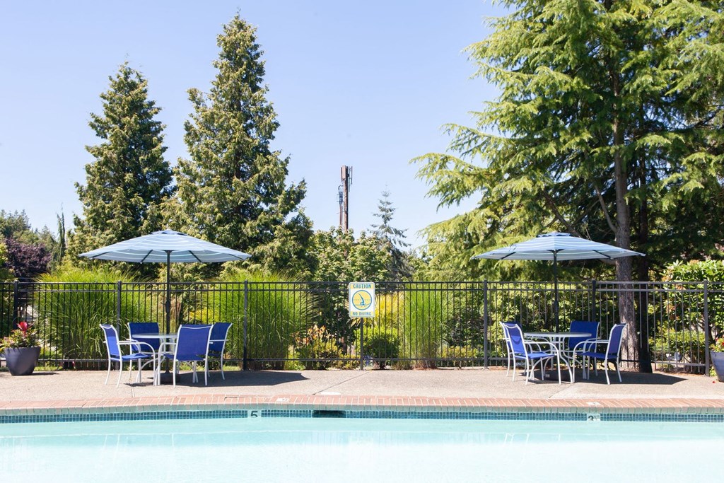a swimming pool with blue chairs and umbrellas next to a resort pool