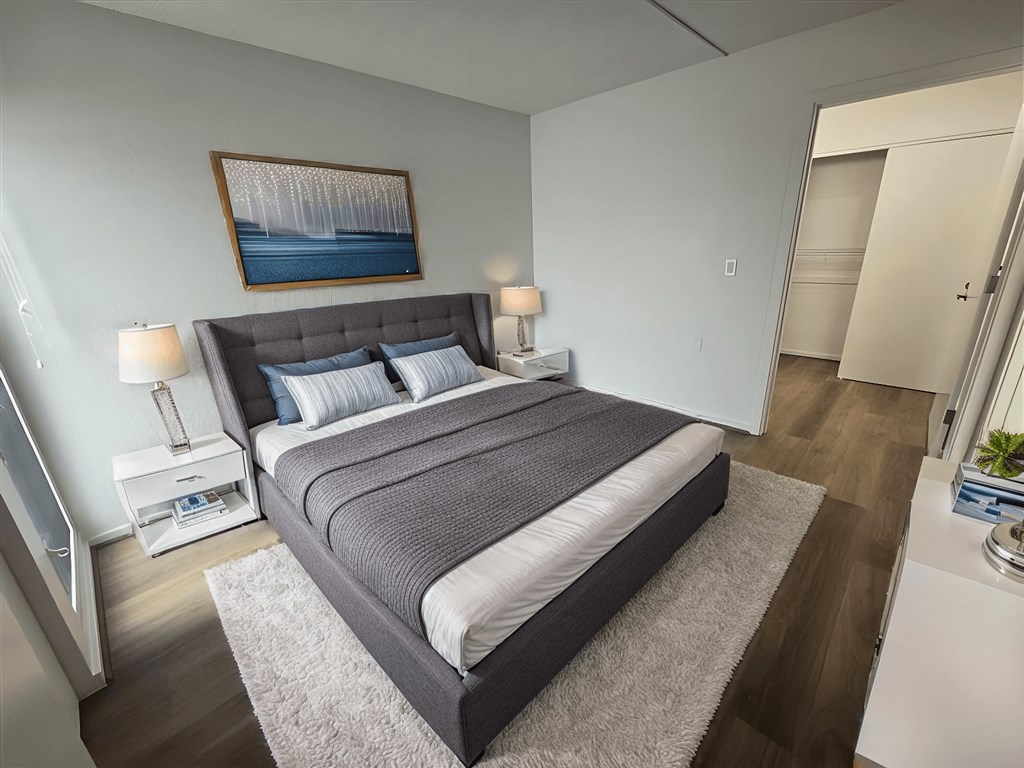 A bedroom with a large bed and a painting on the wall.