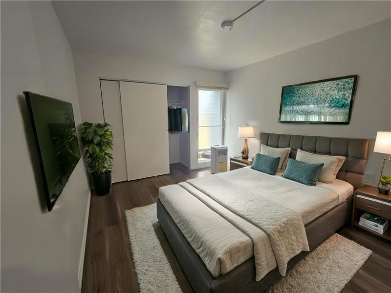 A bedroom with a large bed and a painting on the wall.