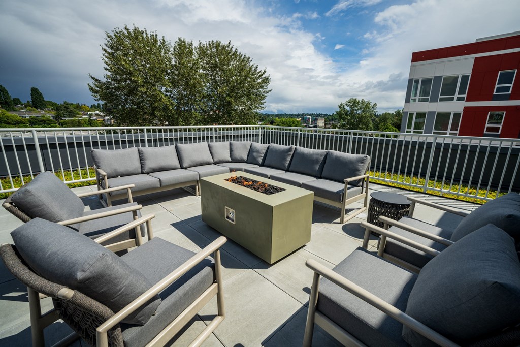 the terrace of a building with couches and chairs and a fire pit