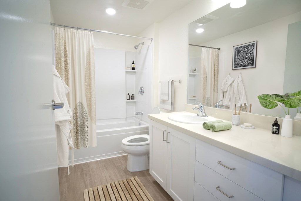 A white bathroom with a toilet, sink, and shower.