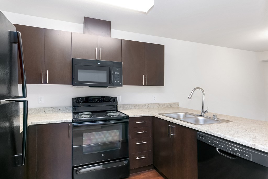an empty kitchen with black appliances and granite counter tops
